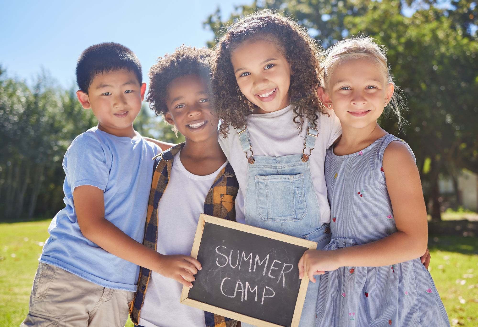 Kids smiling and holding a Summer Camp sign